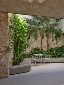 Outdoor space featuring modern design with concrete walls and chairs surrounded by greenery.