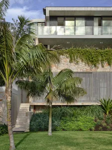A modern residential building featuring stone, glass, and metal materials.
