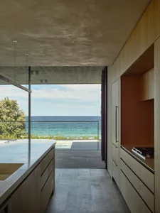 A modern residential kitchen with wooden elements and a view of the ocean.
