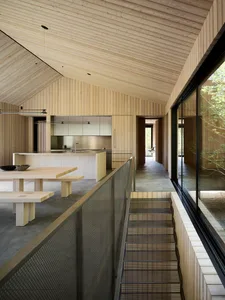 A modern kitchen with wooden walls and ceiling, stainless steel appliances, and a dining table.