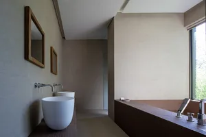 Modern minimalist bathroom with concrete walls, minimalist sink, and large window allowing natural light.