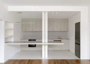 A modern minimalist kitchen with concrete countertops and white cabinets.