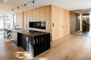 A modern minimalist kitchen with wooden cabinets and a black island.