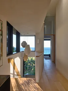 Modern, minimalist corridor with wood flooring and a view of the ocean through large windows
