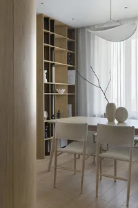Modern dining room featuring wooden furniture, white curtains, and minimalist decor.