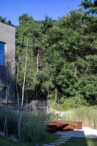Modern exterior featuring corten steel bench and gravel pathway in a greenery setting.
