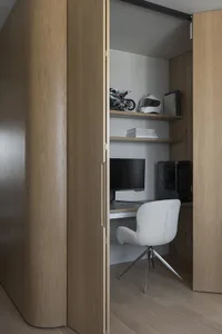 A modern home office with a wooden desk, shelves, and a white chair.
