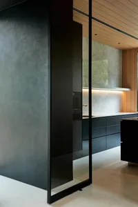 A modern kitchen with sleek concrete walls and large glass features.