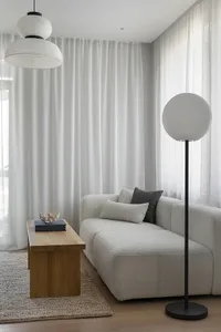 A modern living room featuring a light-colored fabric couch, wooden coffee table, and floor lamp with a round white shade.