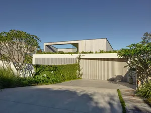 Modern minimalist house with concrete and glass exterior, featuring clean lines and an open layout, set against a clear blue 
