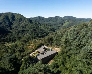 俯瞰一座位於山區林地中的現代極簡混凝土住宅外觀。