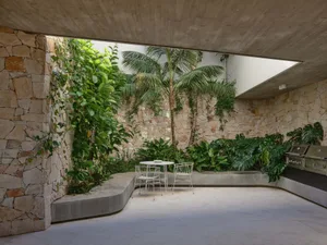 Outdoor living space featuring modern design with stone, concrete, and lush greenery.