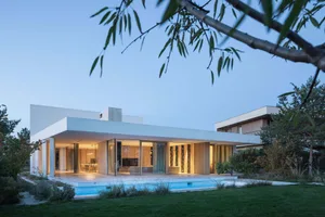 Modern residential home with concrete exterior, glass doors, and swimming pool in a serene outdoor setting.