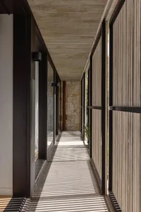 A modern wooden corridor with long shadows cast by natural light.