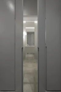 A minimalist bathroom featuring a modern concrete sink and floor, with a small mirror and light fixture.