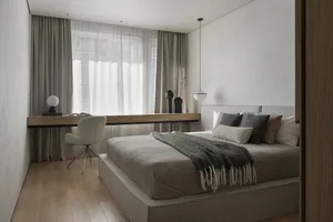 A stylish, minimalist bedroom featuring a bed with a fabric and wood frame, glass-topped floating desk, and a glass vase.