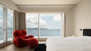 A minimalist bedroom with a glass window overlooking the ocean.