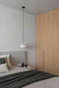 Minimalist bedroom featuring wooden features and a bed with pillows and a blanket.
