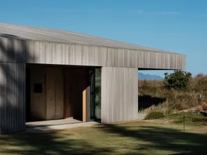 Modern minimalist residential home featuring wood and concrete materials with a landscaped garden.