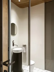 Modern minimalist bathroom featuring concrete sink, glass shower enclosure, and metal fixtures.