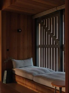 A cozy wooden window seat with cushions and a pillow, featuring a minimalist design.