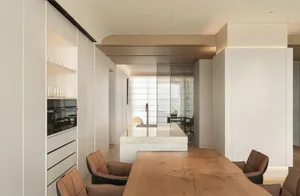Modern kitchen with wooden table, marble island, and sleek appliances