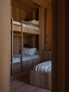 A minimalist bedroom featuring wood twin bunk beds with striped bedding.