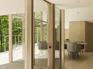 A minimalist living room with large glass sliding doors and wooden flooring.