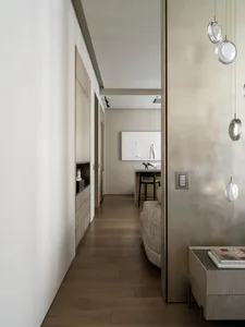 A modern minimalist living room featuring a white color palette with wooden furniture, concrete walls, and metal accents.