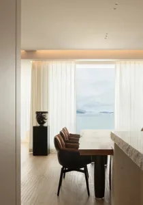 A modern neutral-tone living room with a view of the sea.