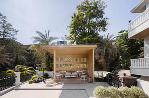 A modern patio featuring a wooden pergola structure, concrete floor, and metal railings.