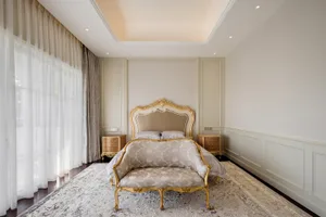 A classical bedroom featuring upholstered furniture and ornate details.