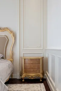 A luxurious bedroom featuring a wooden side table with gold trim.