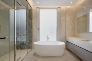 A minimalist bathroom featuring a freestanding bathtub, a walk-in shower, and a vanity with sleek marble countertops.