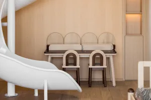 A minimalist children's playroom featuring wooden furniture and a white slide.