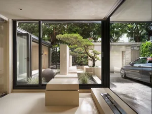 A minimalist living room with concrete materials and a bonsai tree in the center.