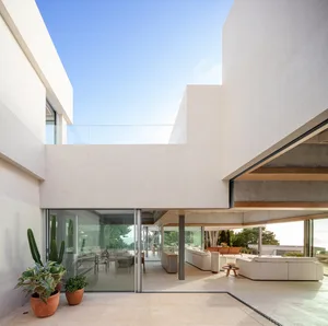 A modern, minimalist patio area with white concrete walls and floors, featuring a glass balcony and large open space with sea