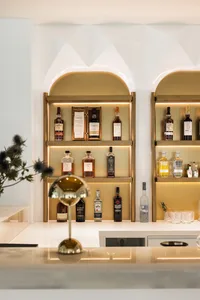 A sleek modern bar with metal shelves displaying various bottles of spirits and a white counter.
