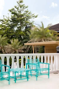 A modern balcony with glass furniture, featuring white railings and greenery.