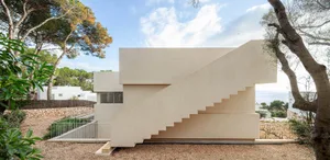 A modern house with a concrete exterior features a unique stepped staircase.
