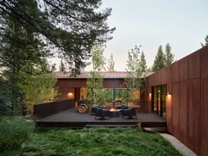 Modern industrial residential exterior with metal siding and a fire pit on the patio.