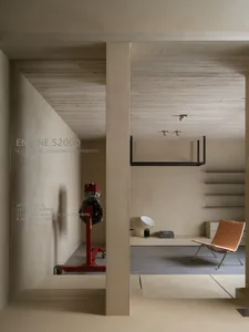 A minimalist interior space with concrete walls and a red mechanical engine on a cart.