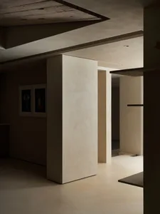 A minimalist interior design featuring concrete walls and flooring, with a focus on clean lines and open spaces.