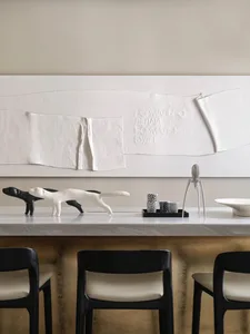 A minimalist interior design featuring concrete and white materials, with a white modern sculpture of a cat and black-and-whi