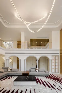 A modern living room featuring a mid-century sofa, coffee table, and arched columns with a stylish rug and white ceiling.
