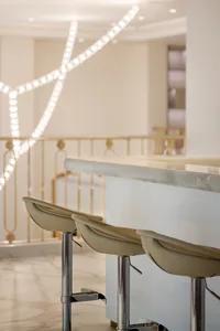 A modern bar counter with white marble top, viewed from a low angle with stools.