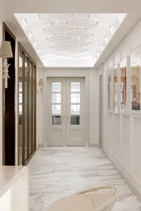 Modern minimalist corridor with marble floor, glass doors, and metallic accents.
