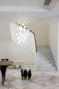 A modern interior space featuring a grand staircase with marble steps and a white marbled floor.