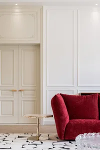 A modern minimalist living room featuring a vibrant red upholstered sofa with a sleek, curved design, placed on a geometric-p