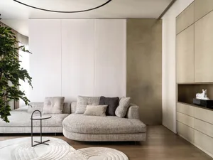 Modern living room with a neutral-toned sofa, circular rug, and minimalist decor.